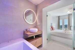 Ein modernes Badezimmer mit rundem Spiegel, Waschbecken und Badewanne.