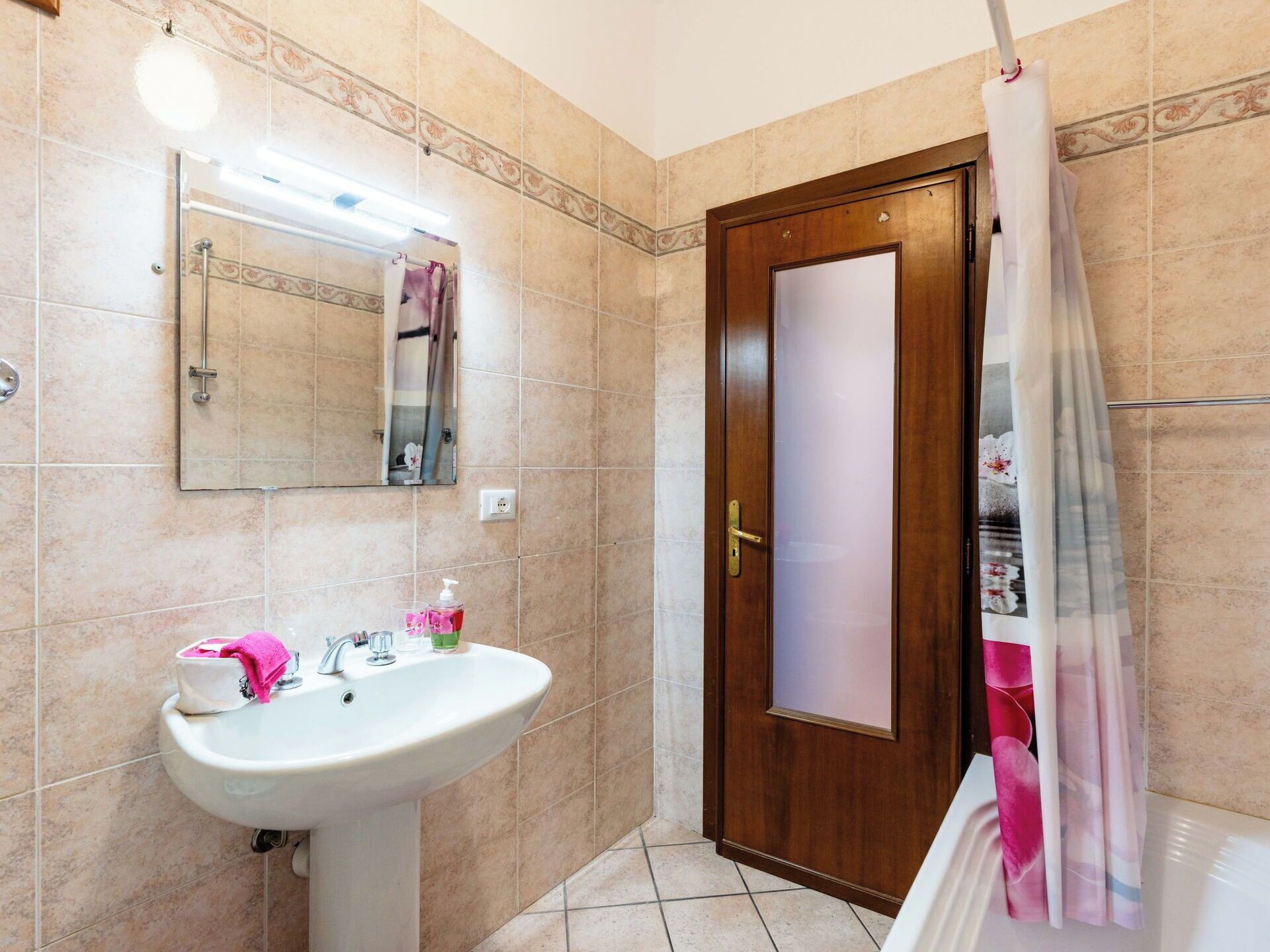 Un baño con lavabo, espejo, cortina de ducha y puerta.