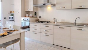 Una cucina moderna con piano cottura a gas, lavello in acciaio inossidabile e pensili chiari.