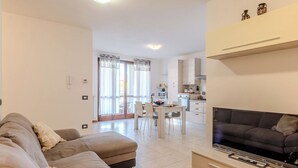 Un soggiorno moderno con divano, TV e zona pranzo con sedie e tavolo.