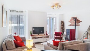 Ein modernes Wohnzimmer mit Flachbildfernseher, Sofas, einem Couchtisch und einem Kamin.