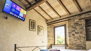Ein Schlafzimmer mit einem Bett, einem an der Wand befestigten Fernseher und einem Fenster.