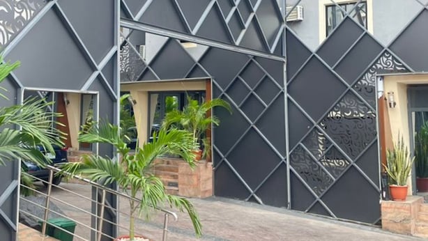 A modern building with a geometric facade, outdoor seating area, and potted plants. - SIX DIAMOND HOTEL OPEBI (Lagos)