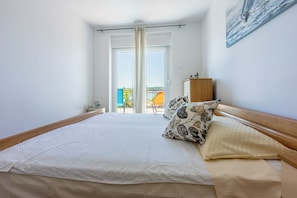 Un dormitorio con una cama grande, cabecera de madera, mesita de noche, armario y vistas al exterior.
