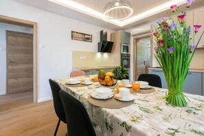 Un comedor con una mesa dispuesta para el desayuno, un microondas y una cocina al fondo.