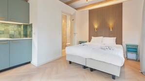 Ein modernes Schlafzimmer mit Bett, Nachttisch, integriertem Kleiderschrank und einer Küchenzeile.