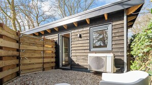 Eine Holzhütte mit einer Schiebetür, einem Fenster und einer Klimaanlage.