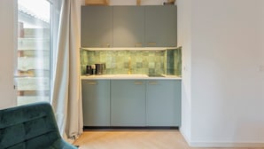 A modern kitchen with light blue cabinets, a white countertop, and a window with curtains. - Studio Linde - in the serene woods of Aerdenhout (Aerdenhout)