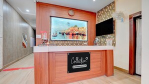 A reception desk with a television, a clock, and a sign indicating it's a company-serviced collection point. - Classic The Century Plaza Hotel (Varanasi)