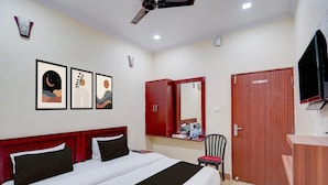 A hotel room with a bed, a wardrobe, a mirror, a chair, and a television. - Classic The Century Plaza Hotel (Varanasi)