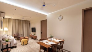 Una sala de estar moderna con sofá, sillón, mesa de centro y mesa de comedor para cuatro.