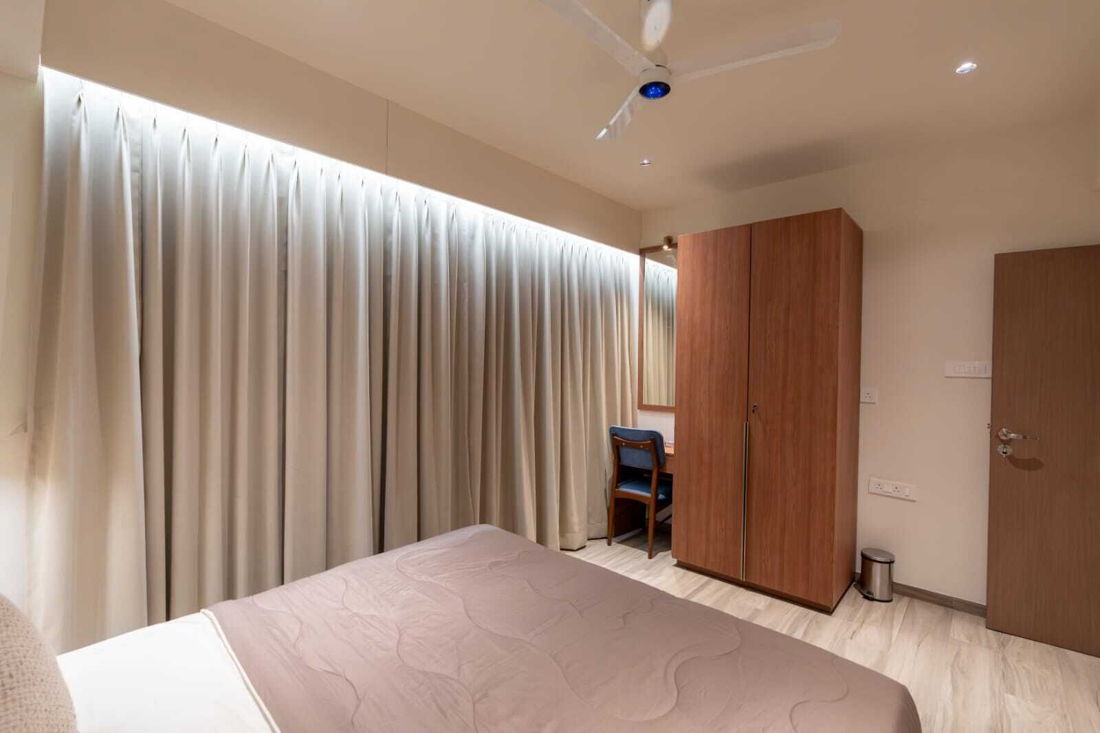 Un dormitorio con una cama, un armario, un escritorio y un ventilador de techo.