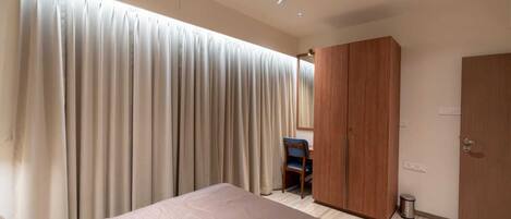 Un dormitorio con una cama, un armario, un escritorio y un ventilador de techo.