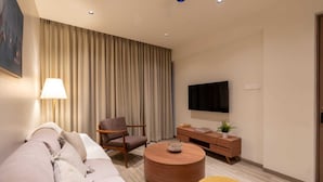 Una sala de estar moderna con sofá, sillón, mesa redonda de centro y televisor de pantalla plana montado en la pared.