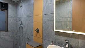 Un baño moderno con inodoro, bidé y lavamanos, que cuenta con un espejo grande e iluminación empotrada.