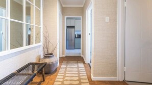 A hallway with a bench, a potted plant, and a view into a kitchen area. - Sol & Sage (Cape Town)