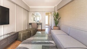 A modern living room with a sofa, ottoman, TV, and a large mirror. - Sol & Sage (Cape Town)