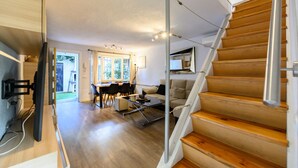 A modern interior with a wooden staircase, a dining area with a table and chairs, and a sofa. - (SAB52) Spacious 3-bedroom villa with terrace (Madrid)
