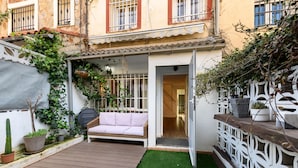 A patio with a wooden deck, a white sofa, and a small garden area with potted plants. - (SAB52) Spacious 3-bedroom villa with terrace (Madrid)