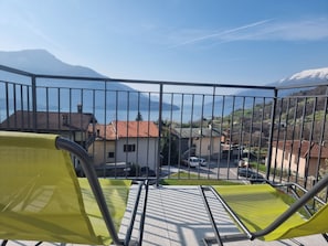 A balcony with yellow chairs, a view of houses, and mountains in the background. - Well House (Vercana)