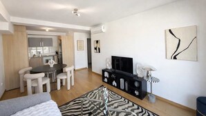 Un appartement moderne comprenant un coin repas, une cuisine, un salon et un téléviseur.