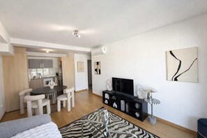 Eine moderne Wohnung mit Essbereich, Küche, Wohnzimmer und Fernseher.