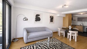 Un salon moderne avec un canapé gris, un tapis à motifs zébrés et des œuvres d’art abstraites accrochées au mur.