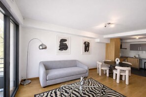 Ein modernes Wohnzimmer mit einem grauen Sofa, einem Teppich mit Zebra-Muster und abstrakter Kunst an der Wand.