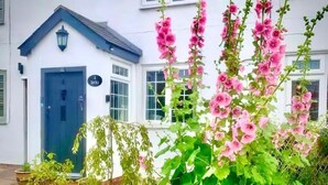 Ein Gebäude mit einer blauen Tür, einem Schild mit der Aufschrift 'Jacky' und einem Garten mit rosa Blumen.
