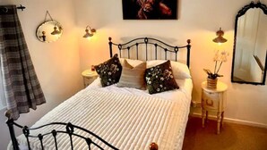 Ein Schlafzimmer mit einem Bett, einem Spiegel, einer Lampe und einem Bild an der Wand.