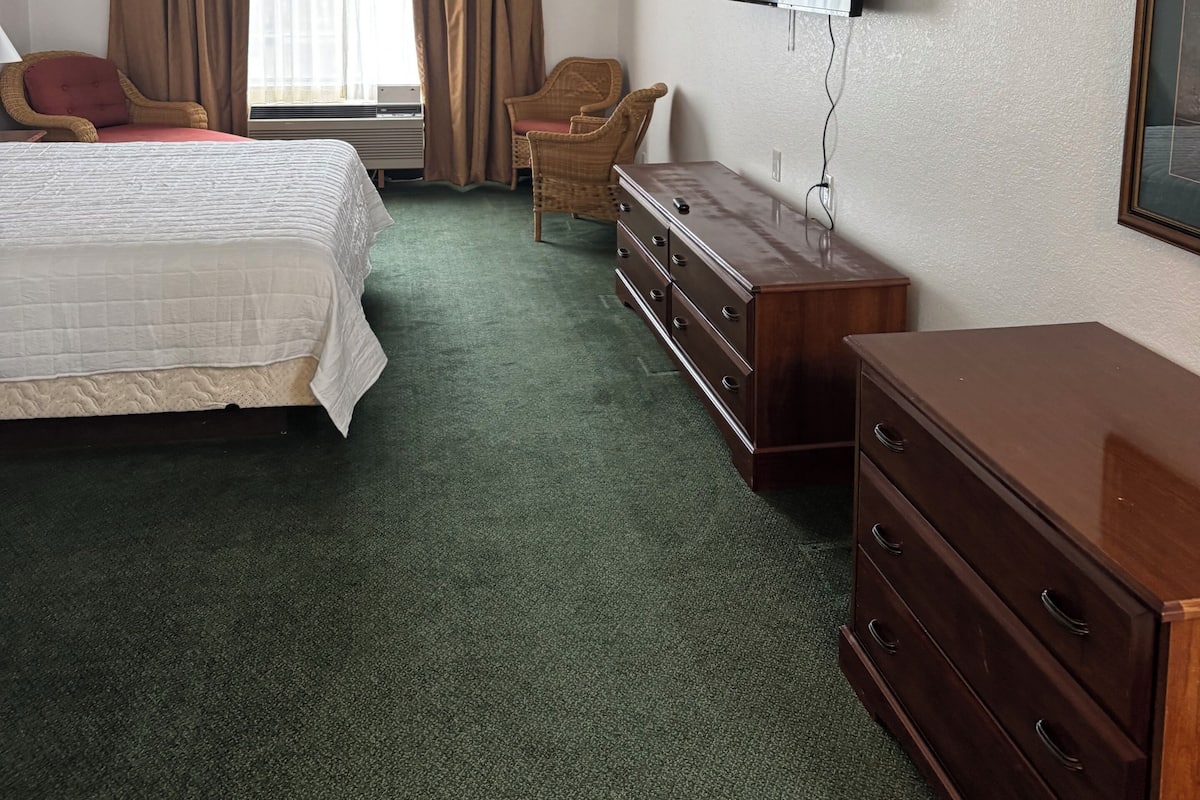 A hotel room with a bed, a dresser, a television, and a chair.