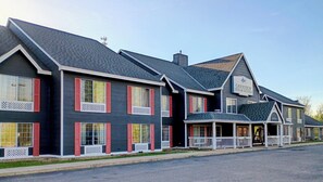 A Garrison Inn & Suites building with a dark facade, red window shutters, and a porch area.