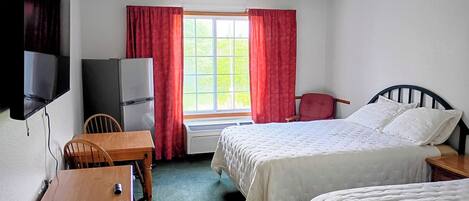 A hotel room with two beds, a TV, a desk, a chair, and a window with curtains.