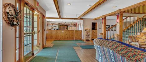 A hotel lobby with wooden floors, a reception desk, a staircase, and a patterned bench.