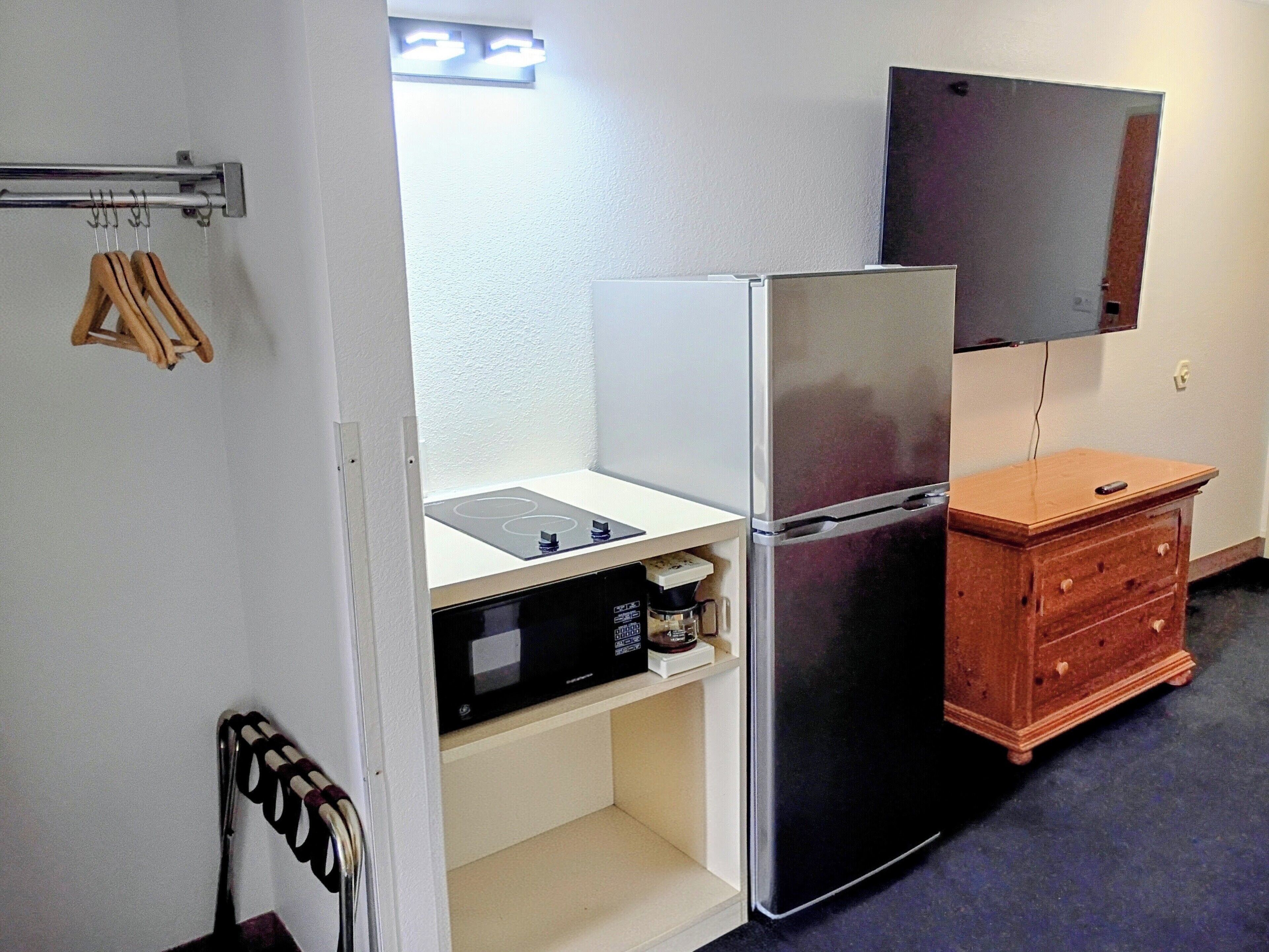A compact kitchen with a refrigerator, microwave, and wooden cabinet.