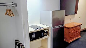 A compact kitchen with a refrigerator, microwave, and wooden cabinet.