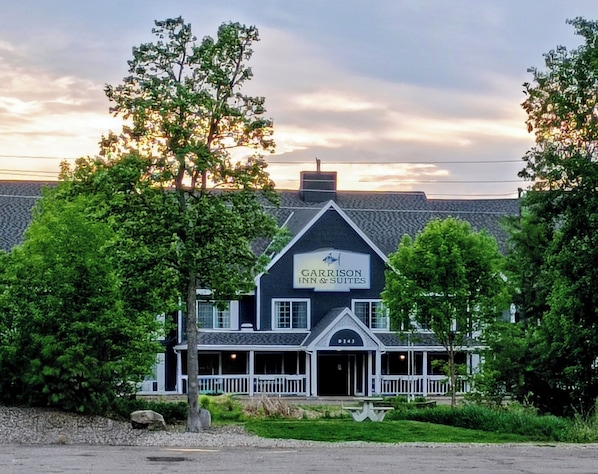 A building with a sign reading 'GARRISON INN & SUITES' with a covered porch and a stone facade. - Garrison Inn & Suites (Garrison)