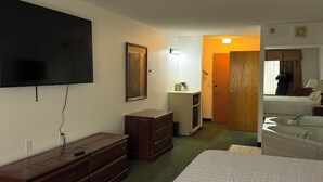 Ein Hotelzimmer mit Bett, Schminktisch, Fernseher und Spiegel.