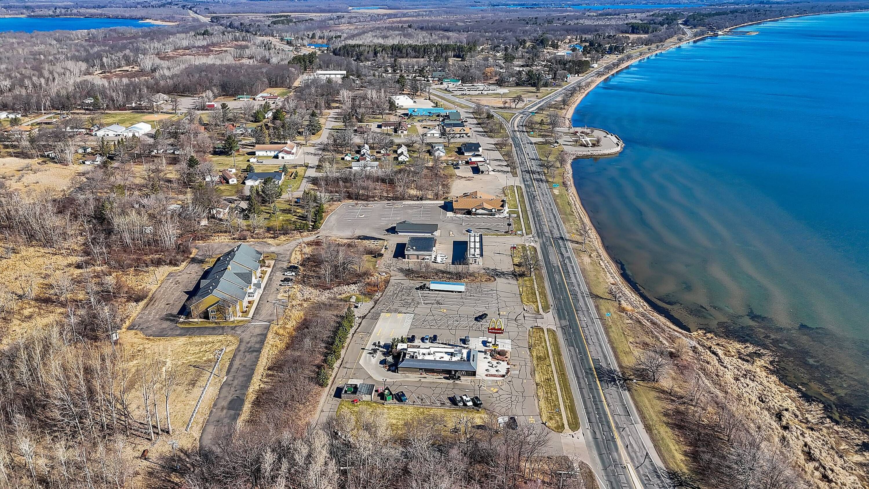 An aerial view of a coastal town with a McDonald's restaurant, a parking lot, and a road leading to the beach.