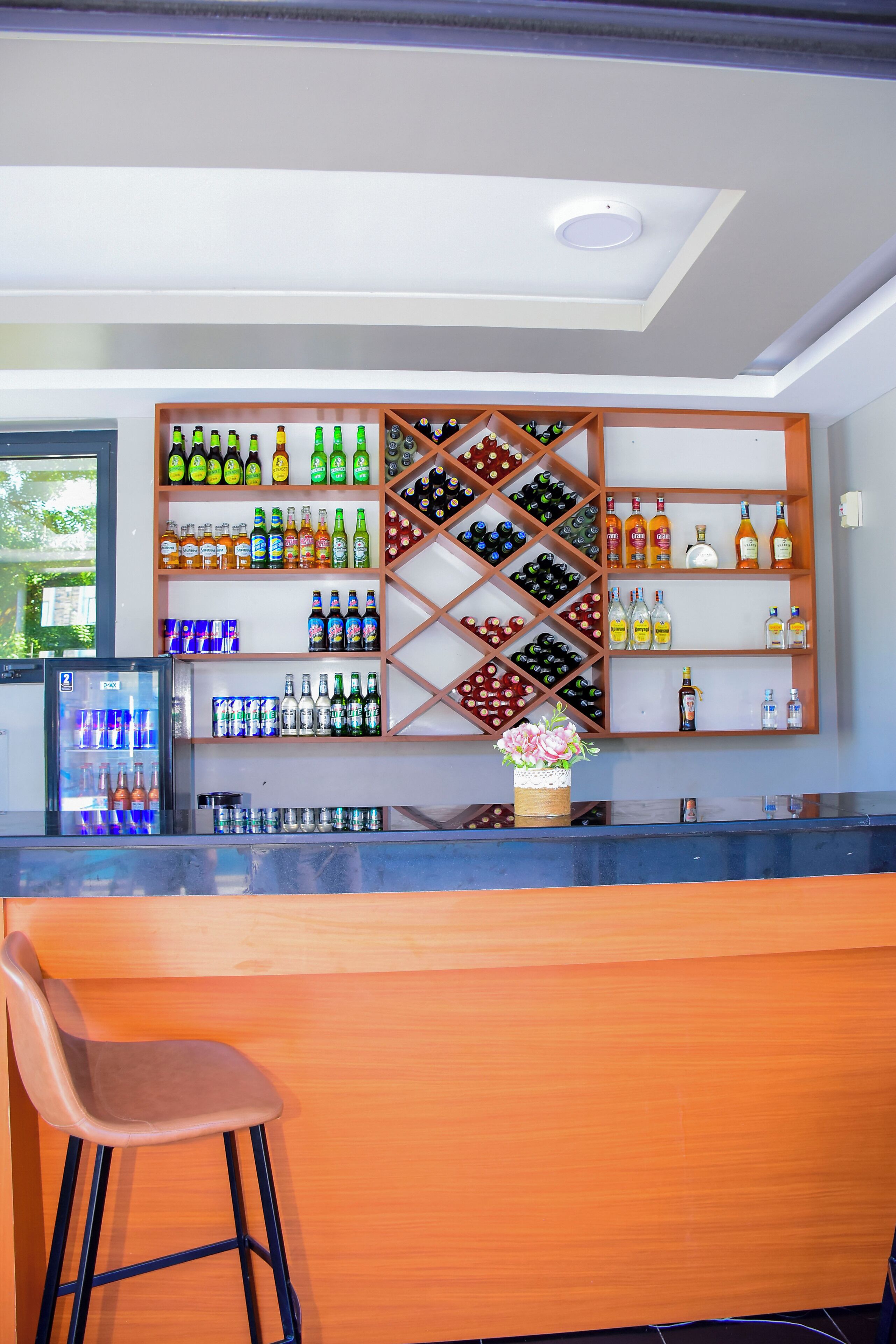 A bar area with shelves of bottled beverages, a refrigerator, and a bar counter.