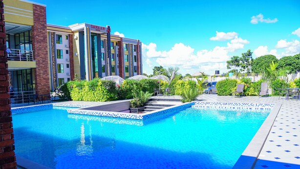 Un hotel con piscina, zona exterior cubierta y un edificio de varios pisos.
