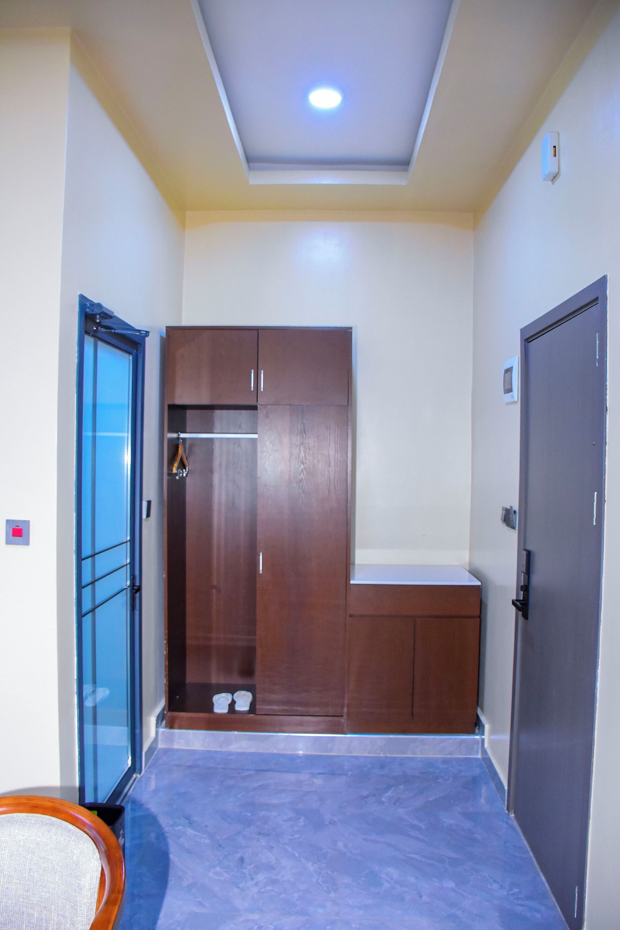 A room with a wardrobe, a door, and a tiled floor.