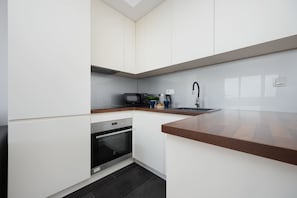 Eine moderne Küche mit weißen Schränken, einer Mikrowelle, einem Spülbecken und einer Holz Arbeitsplatte.