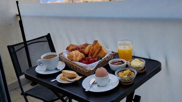 Una mesa con alimentos para el desayuno y vista al mar.