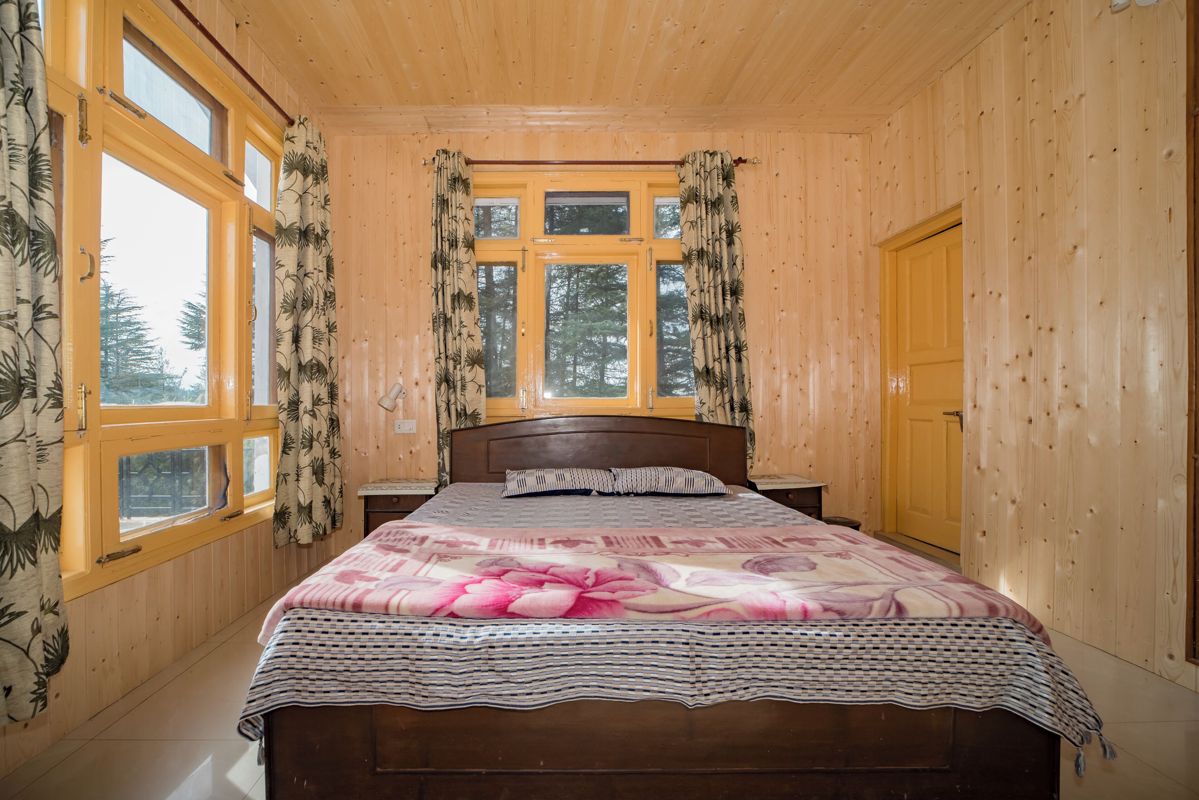 A wooden-paneled bedroom with a bed, curtains, and a window.