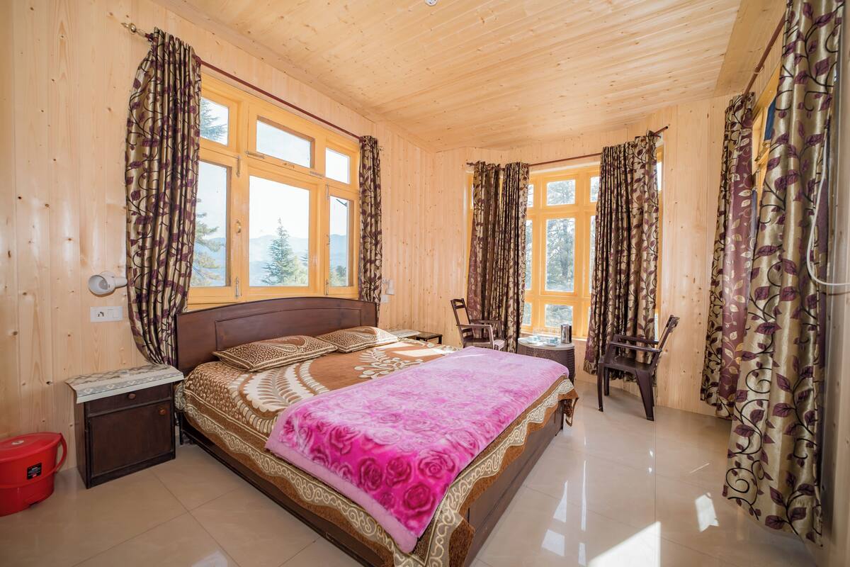 Ein Schlafzimmer mit Holzwandverkleidung, einem Bett, einem Nachttisch, einem Sessel und einem Fenster.
