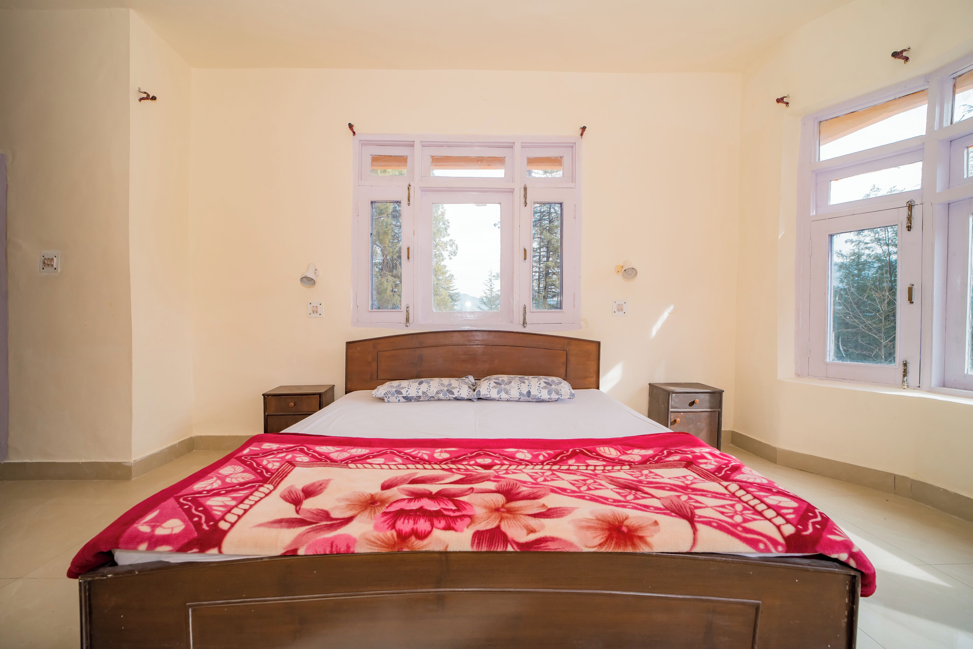 Ein Schlafzimmer mit einem Bett, einem Fenster, einem Nachttisch und einer Steckdose.
