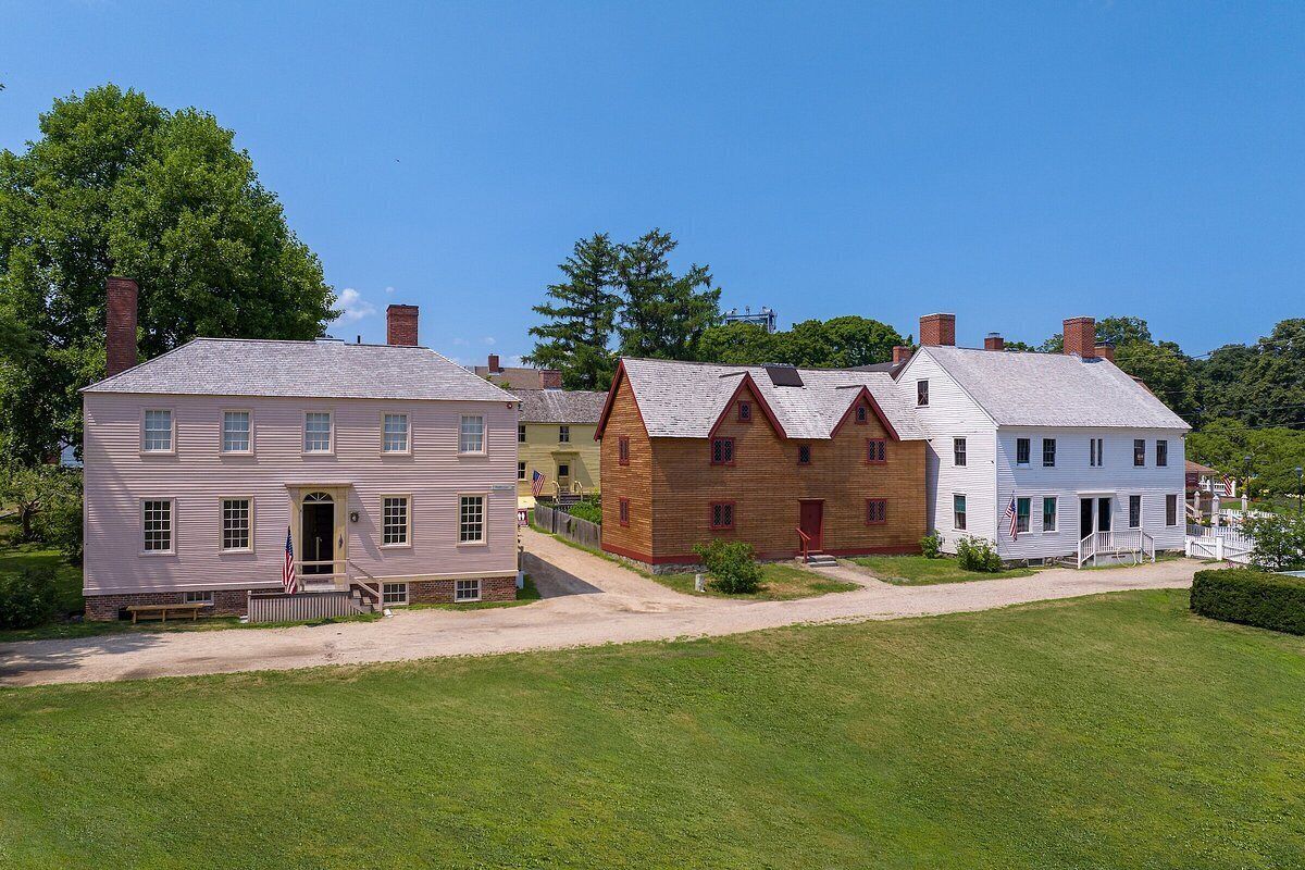 A row of historic houses with a well-maintained lawn and a clear sky.