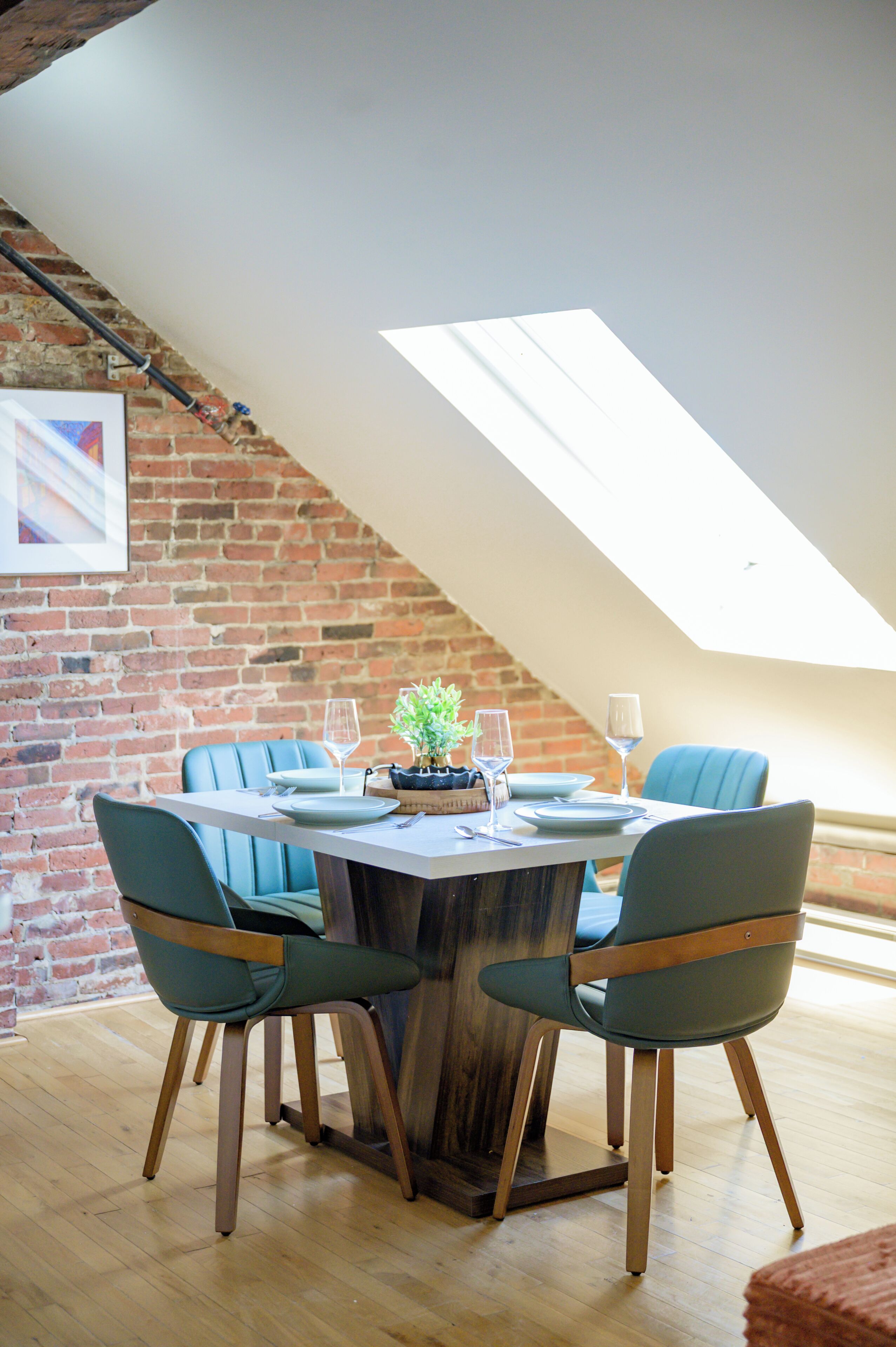 A dining area with a brick wall, a wooden table, and blue chairs.