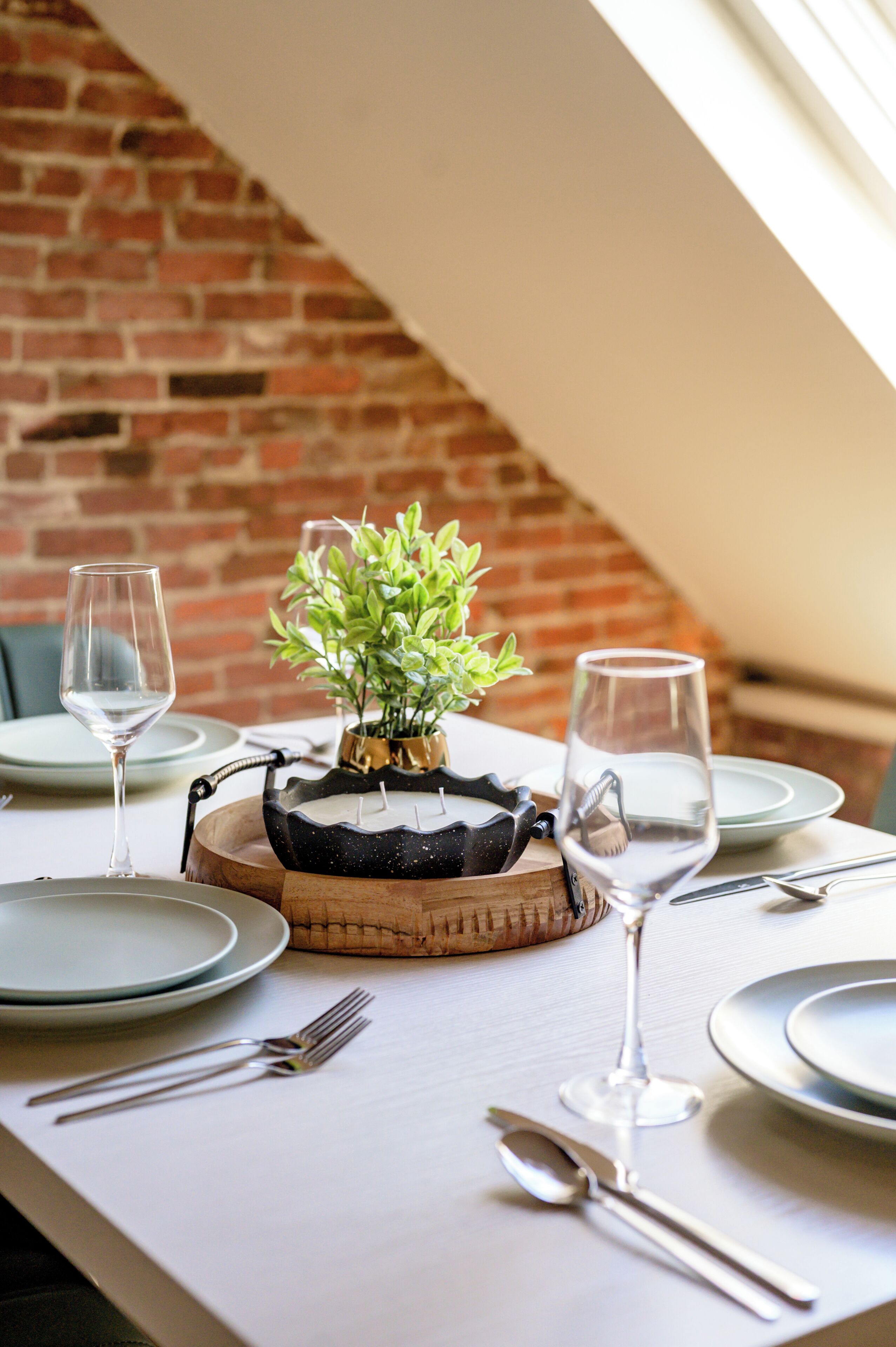 A dining table with plates, cutlery, and a small potted plant.